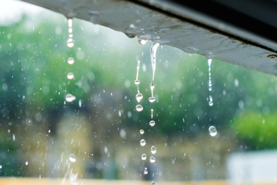 Cose-up of rainwater running off roofline without gutters causing uncontrolled water runoff